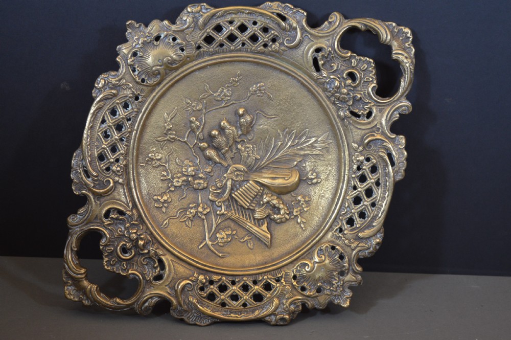 A cast bronze decorative centrepiece plate featuring a high-relief central scene with birds and musical instruments surrounded by an openwork lattice border and scroll handles. View XII