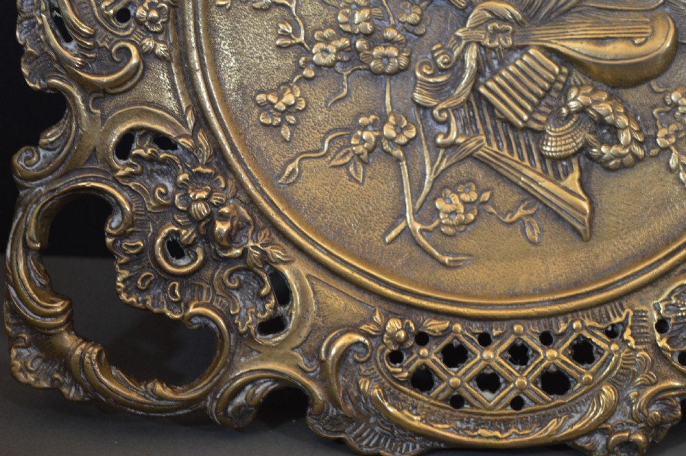 A cast bronze decorative centrepiece plate featuring a high-relief central scene with birds and musical instruments surrounded by an openwork lattice border and scroll handles. View XV