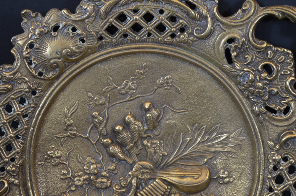 A cast bronze decorative centrepiece plate featuring a high-relief central scene with birds and musical instruments surrounded by an openwork lattice border and scroll handles. View XVI