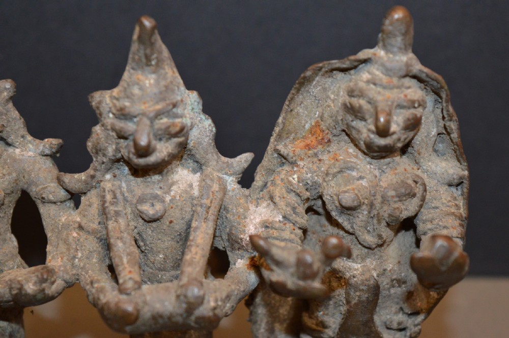 An antique dark bronze Indian sculpture featuring three standing Hindu deities with conical headwear on a shared rectangular base. View II
