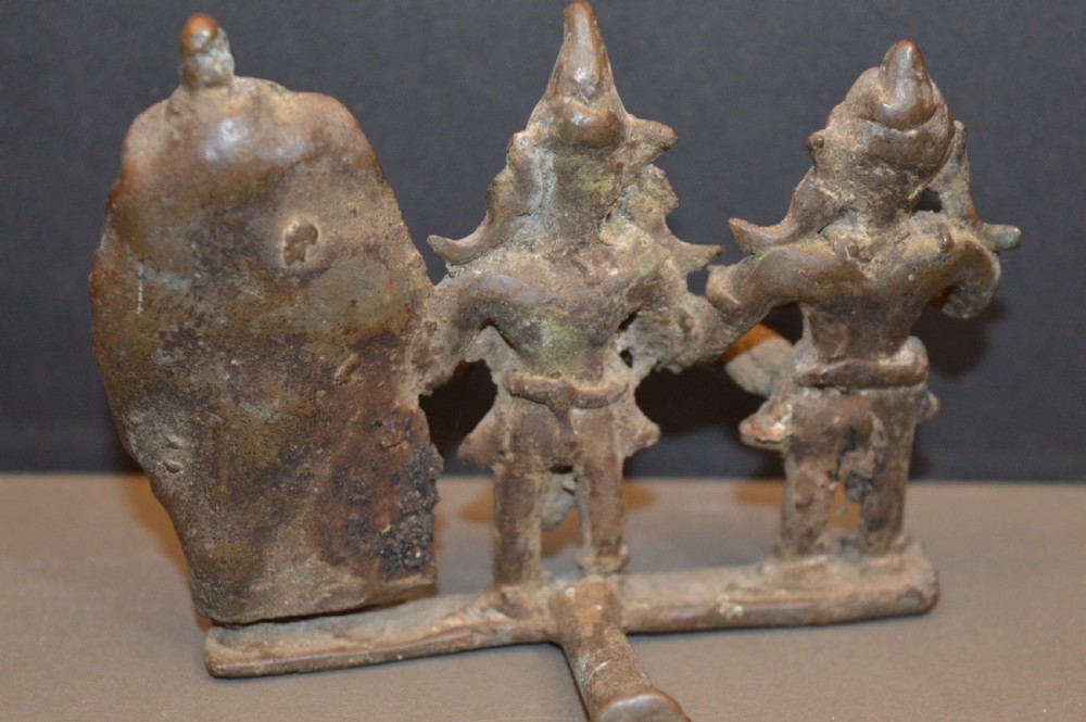An antique dark bronze Indian sculpture featuring three standing Hindu deities with conical headwear on a shared rectangular base. View V