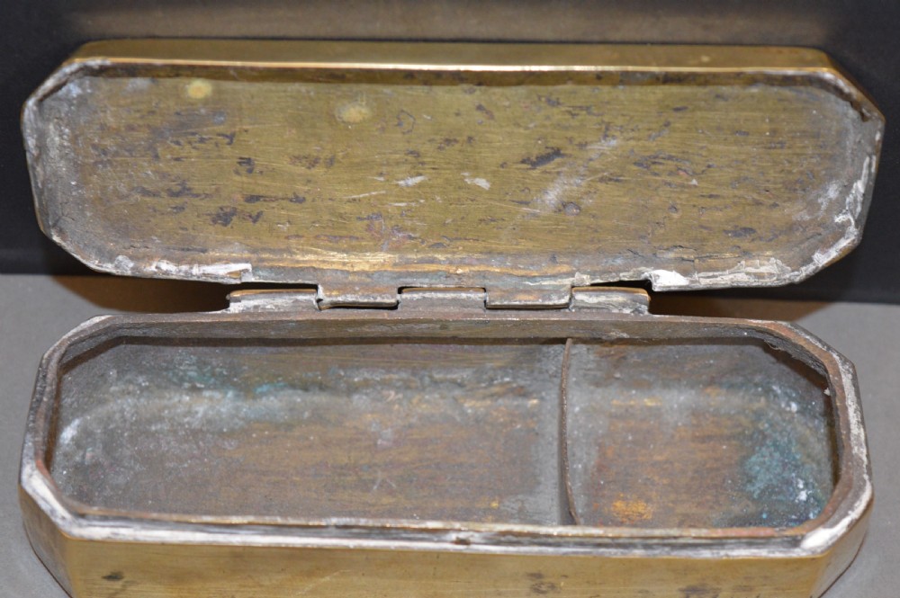 An elongated Georgian brass tobacco box featuring hand-engraved floral motifs, canted corners, and a hinged lid. View VI