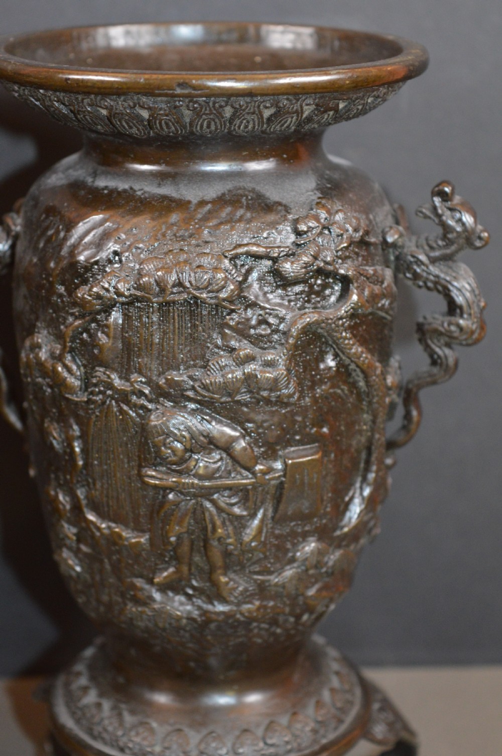 A pair of dark bronze Meiji period Japanese vases with high-relief figural decoration, dragon handles, and tripod bases. View II
