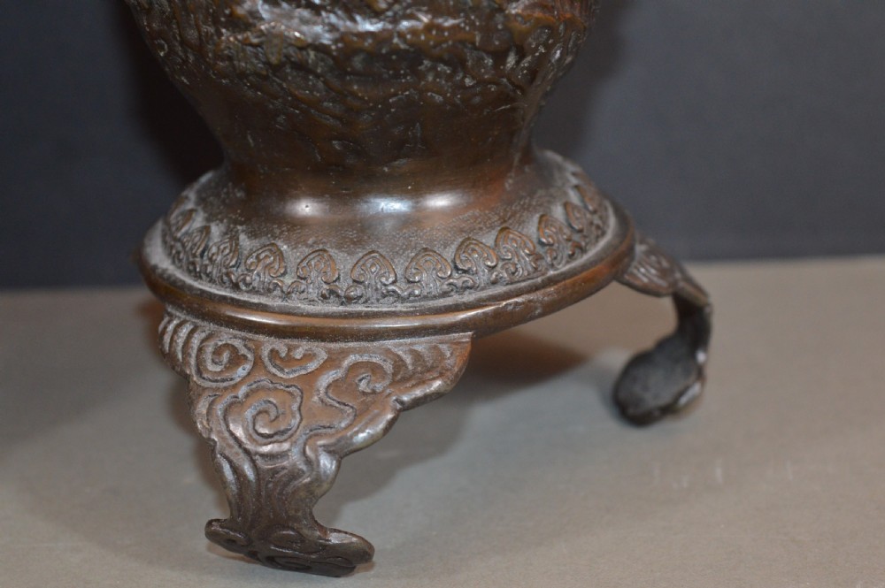 A pair of dark bronze Meiji period Japanese vases with high-relief figural decoration, dragon handles, and tripod bases. View III