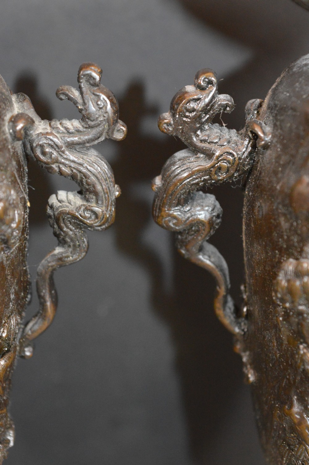 A pair of dark bronze Meiji period Japanese vases with high-relief figural decoration, dragon handles, and tripod bases. View IV