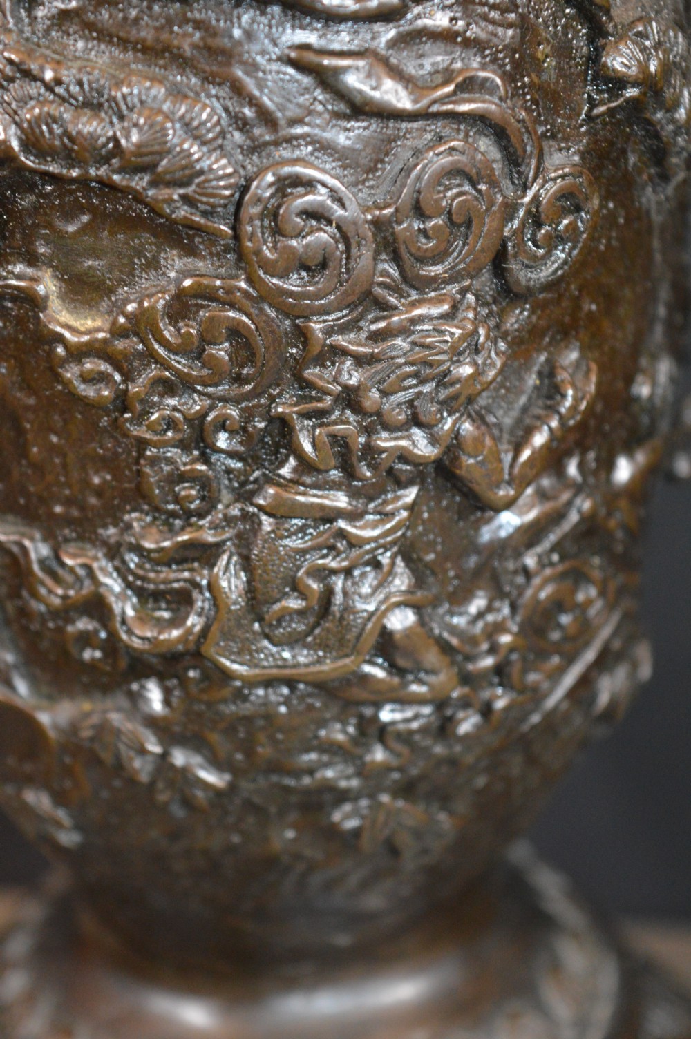 A pair of dark bronze Meiji period Japanese vases with high-relief figural decoration, dragon handles, and tripod bases. View V