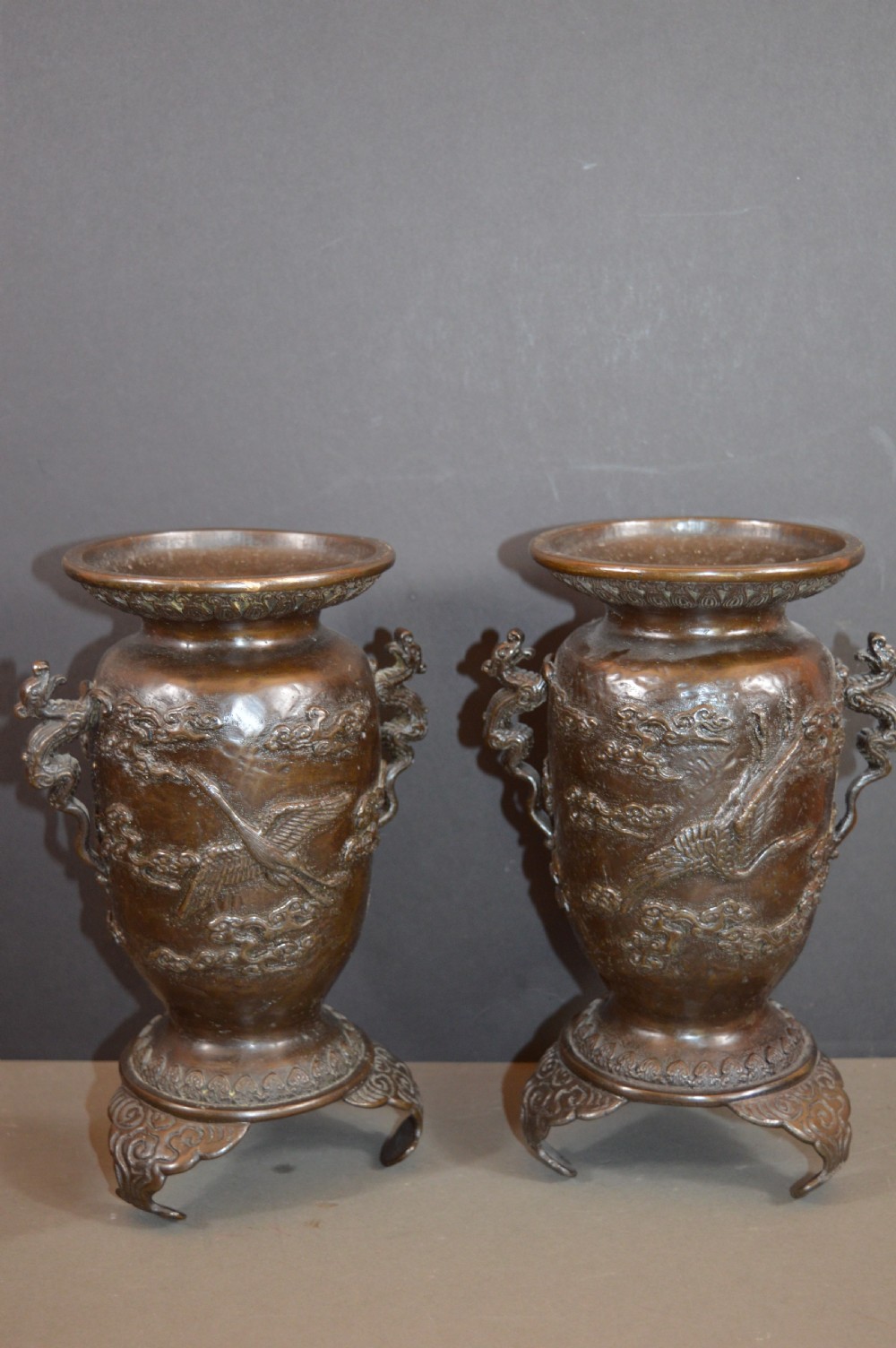 A pair of dark bronze Meiji period Japanese vases with high-relief figural decoration, dragon handles, and tripod bases. View VII