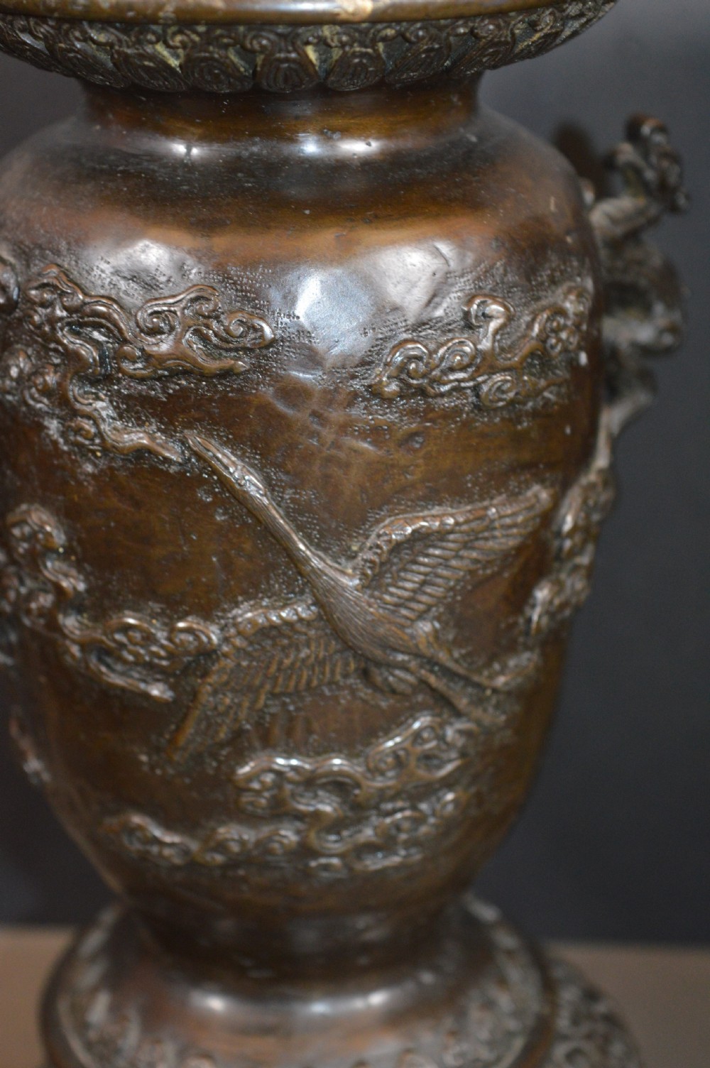 A pair of dark bronze Meiji period Japanese vases with high-relief figural decoration, dragon handles, and tripod bases. View VIII