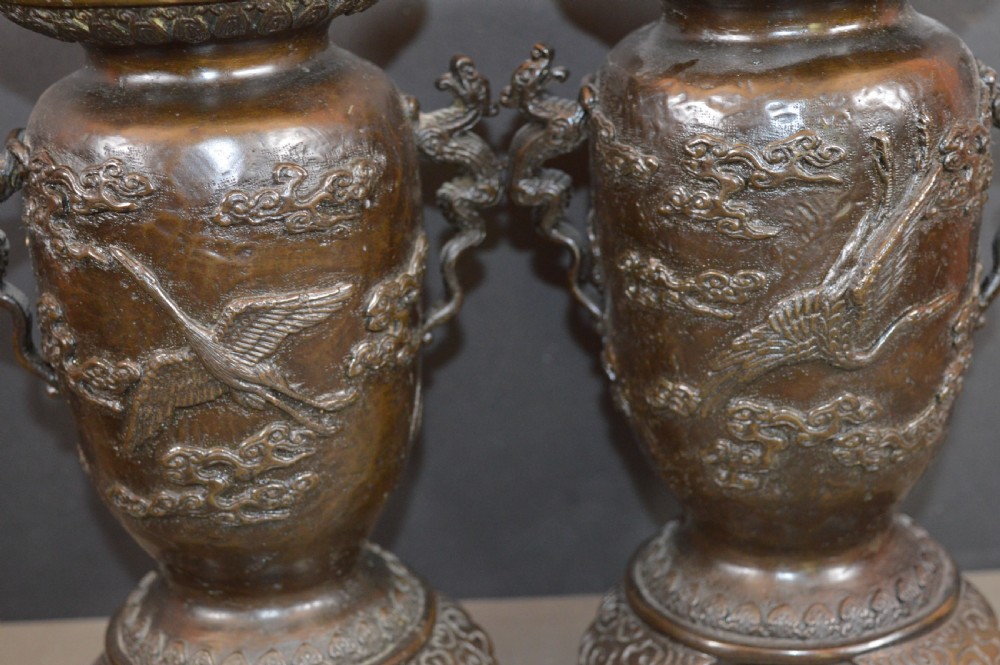 A pair of dark bronze Meiji period Japanese vases with high-relief figural decoration, dragon handles, and tripod bases. View IX