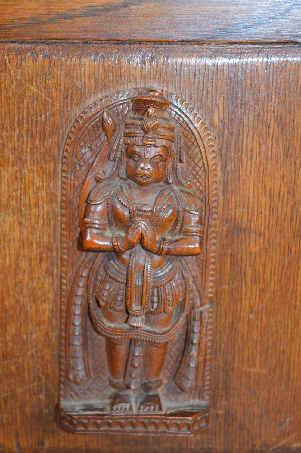 A late 19th-century oak desktop smokers cabinet featuring brass corner mounts and a central relief carving of an Indian deity. View II