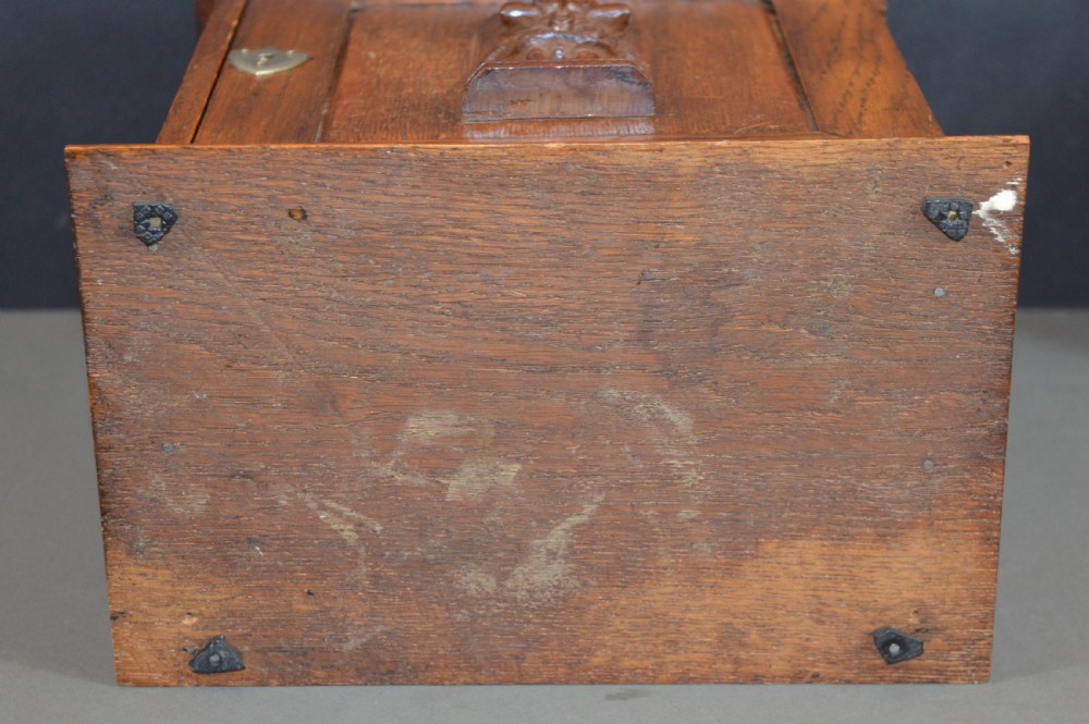 A late 19th-century oak desktop smokers cabinet featuring brass corner mounts and a central relief carving of an Indian deity. View VIII