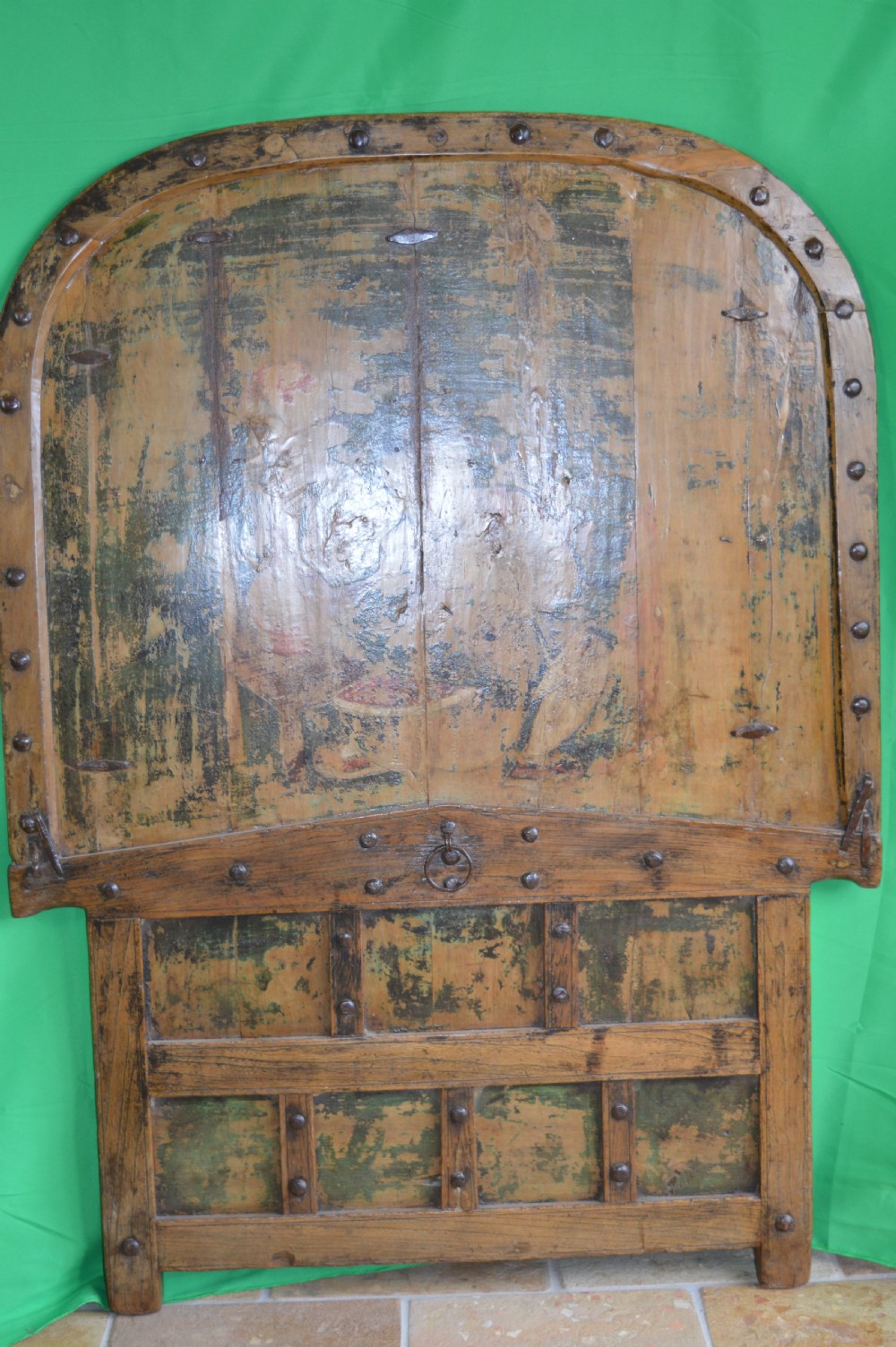 An arched antique Chinese wooden cart door featuring faded hand-painted figures, weathered green pigments, and iron studs. View VI