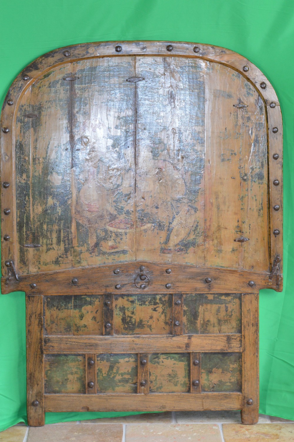 An arched antique Chinese wooden cart door featuring faded hand-painted figures, weathered green pigments, and iron studs. View VII