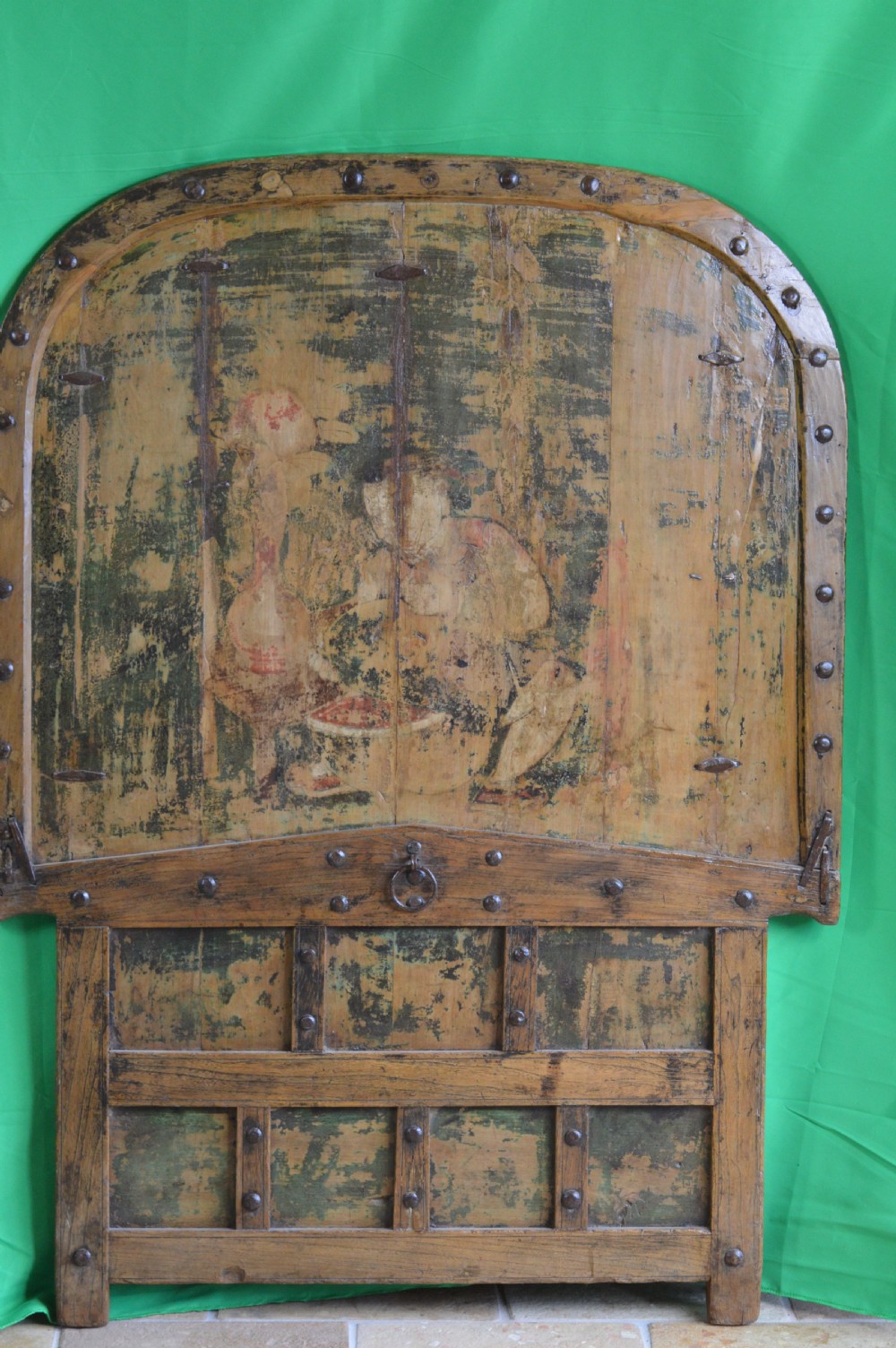 An arched antique Chinese wooden cart door featuring faded hand-painted figures, weathered green pigments, and iron studs. View VIII