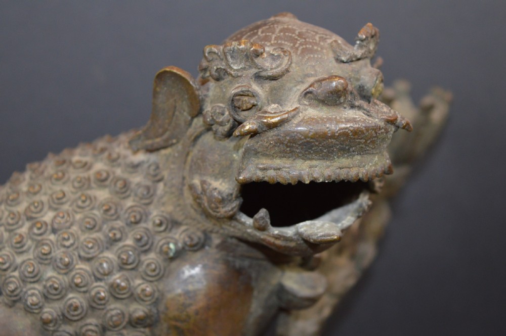 A late 18th-century Chinese bronze incense burner in the shape of a mythical Qilin creature with an open mouth standing on a pierced rectangular stand. View II