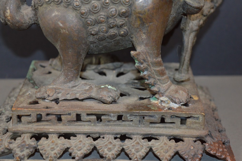 A late 18th-century Chinese bronze incense burner in the shape of a mythical Qilin creature with an open mouth standing on a pierced rectangular stand. View IV