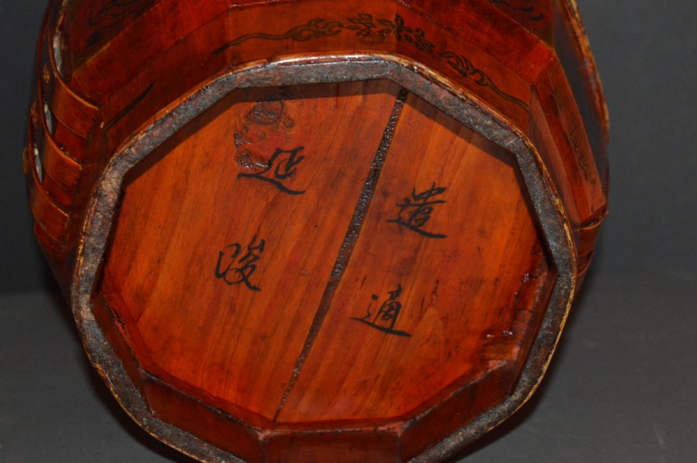 A red hand-painted Chinese wooden rice carrier featuring an arched overhead handle, lidded faceted body, and depictions of waterbirds and fish. View VII