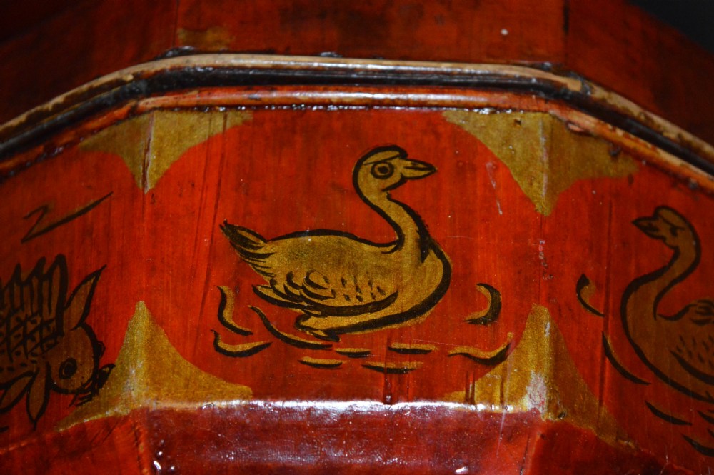 A red hand-painted Chinese wooden rice carrier featuring an arched overhead handle, lidded faceted body, and depictions of waterbirds and fish. View VIII