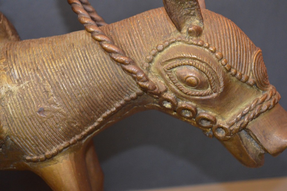 A cast metal Benin style sculpture of a warrior riding a decorated horse on a rectangular base, holding reins and a blade. View IX