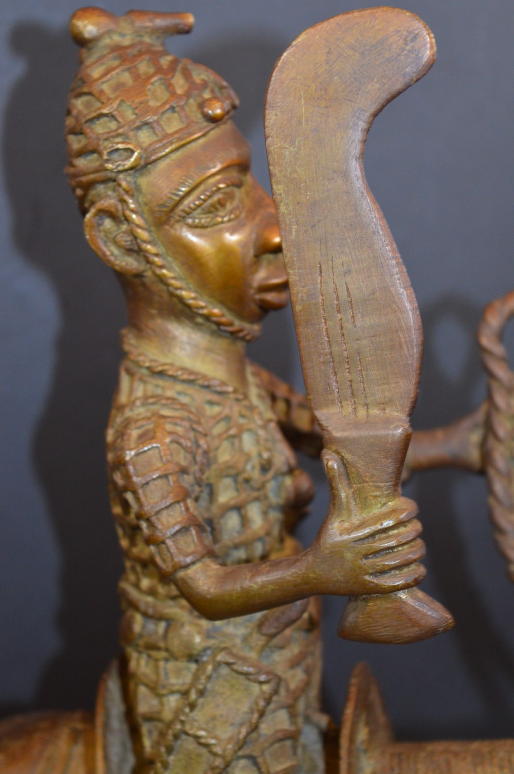 A cast metal Benin style sculpture of a warrior riding a decorated horse on a rectangular base, holding reins and a blade. View X