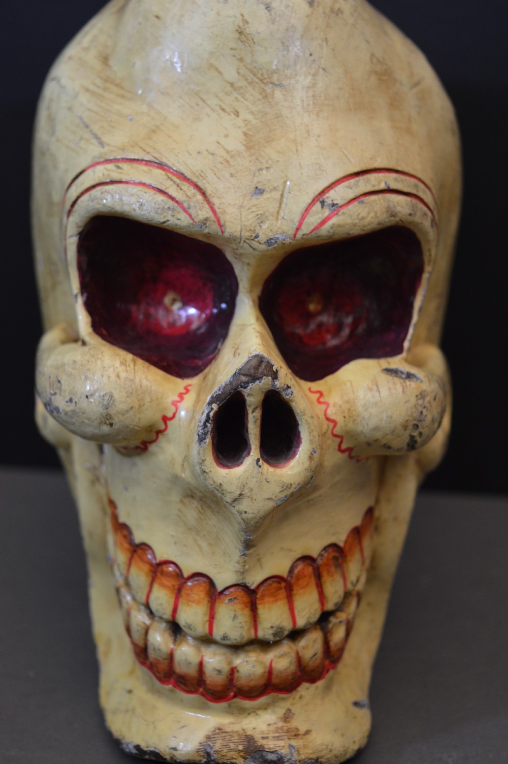 A hand-carved and painted yellow wooden Tibetan Citipati skull featuring deep red eye sockets and sculpted teeth. View VI