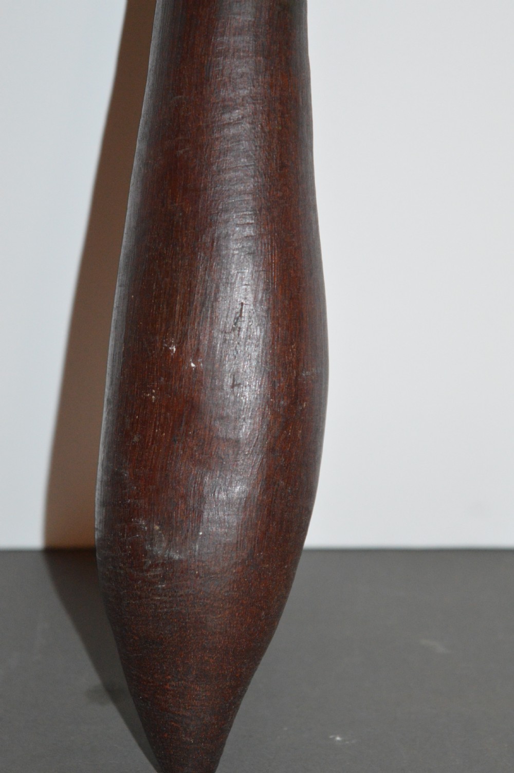 A hand-carved dark hardwood Aboriginal throwing club tapering at both ends with a smooth patinated surface. View II
