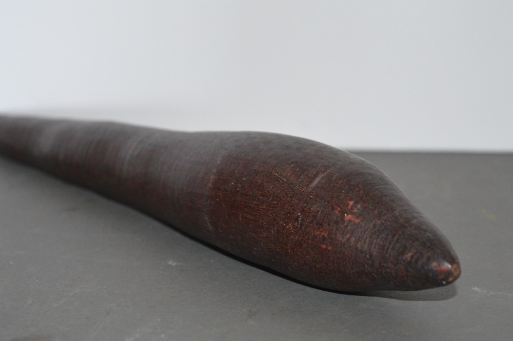 A hand-carved dark hardwood Aboriginal throwing club tapering at both ends with a smooth patinated surface. View IV