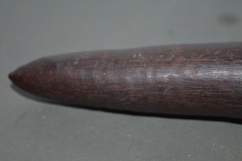 A hand-carved dark hardwood Aboriginal throwing club tapering at both ends with a smooth patinated surface. View VI