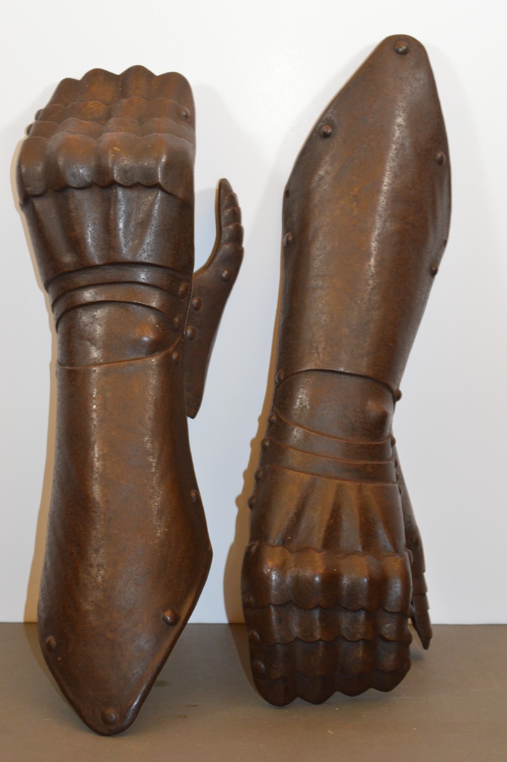 A pair of 19th-century articulated iron armour gauntlets with layered finger plates, flared cuffs, and visible rivets with an oxidised patina. View III