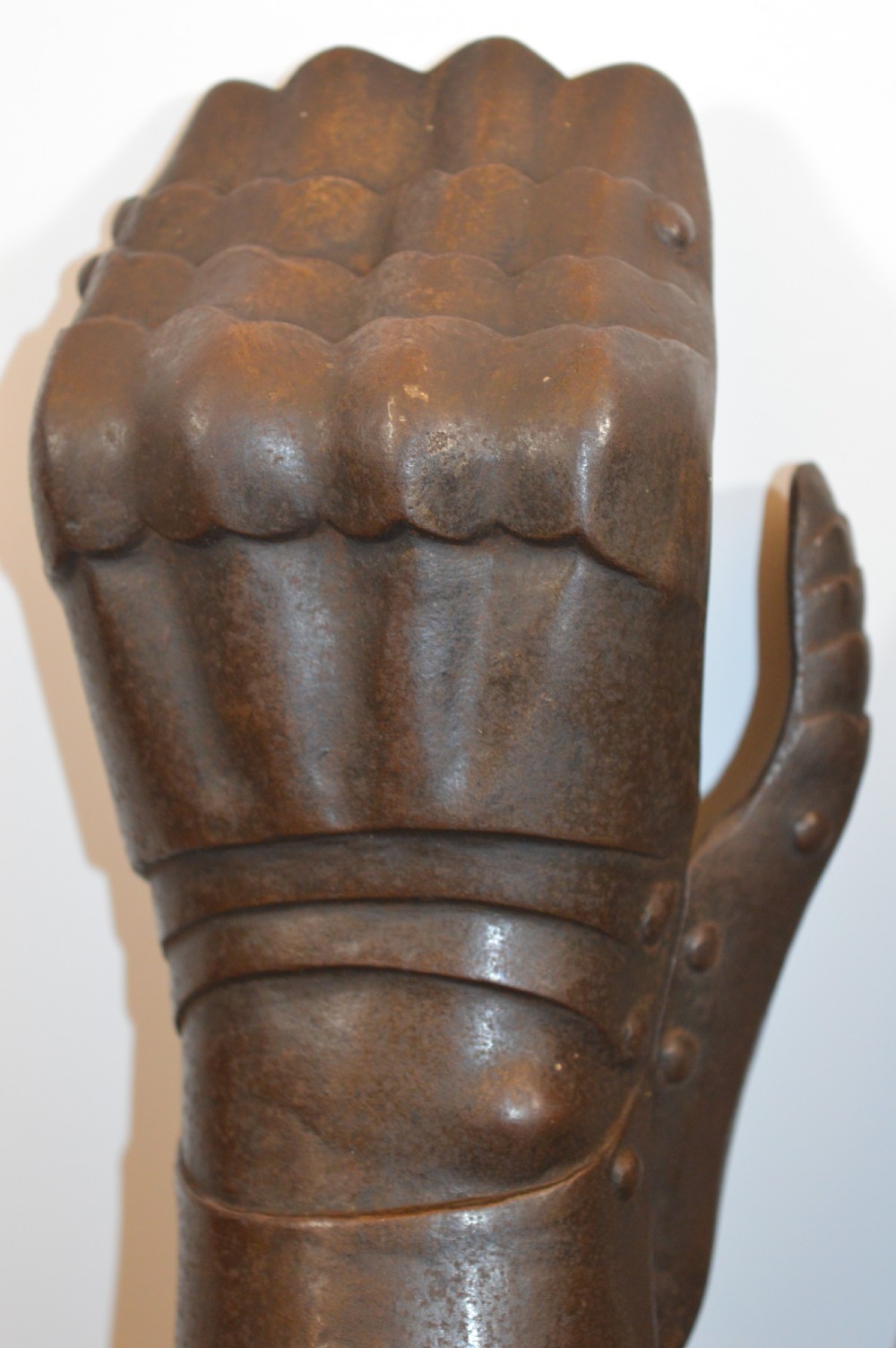 A pair of 19th-century articulated iron armour gauntlets with layered finger plates, flared cuffs, and visible rivets with an oxidised patina. View IV