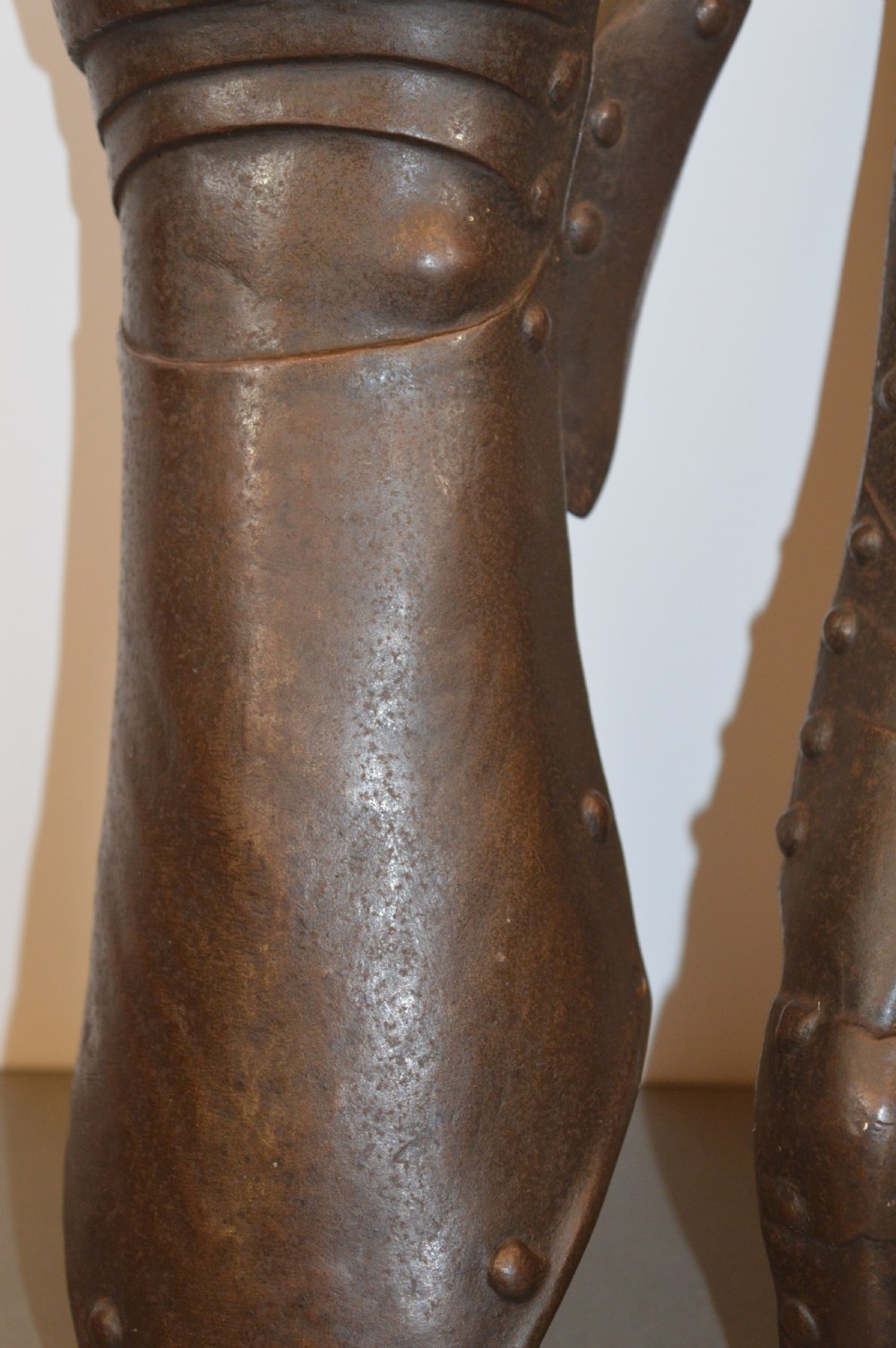 A pair of 19th-century articulated iron armour gauntlets with layered finger plates, flared cuffs, and visible rivets with an oxidised patina. View V