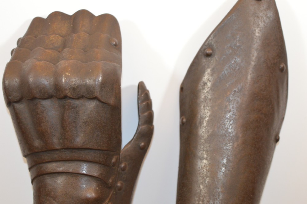 A pair of 19th-century articulated iron armour gauntlets with layered finger plates, flared cuffs, and visible rivets with an oxidised patina. View VII