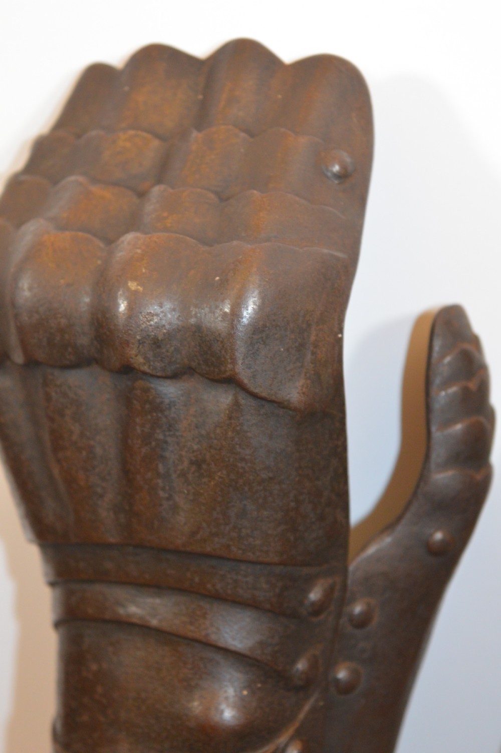 A pair of 19th-century articulated iron armour gauntlets with layered finger plates, flared cuffs, and visible rivets with an oxidised patina. View VIII