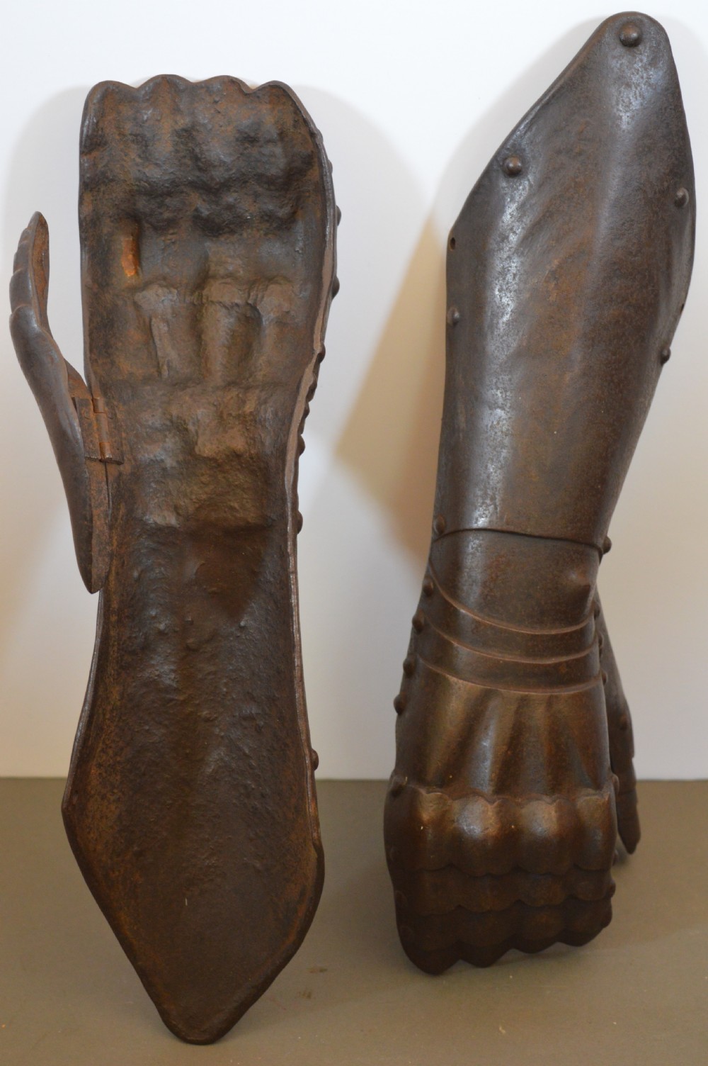 A pair of 19th-century articulated iron armour gauntlets with layered finger plates, flared cuffs, and visible rivets with an oxidised patina. View IX