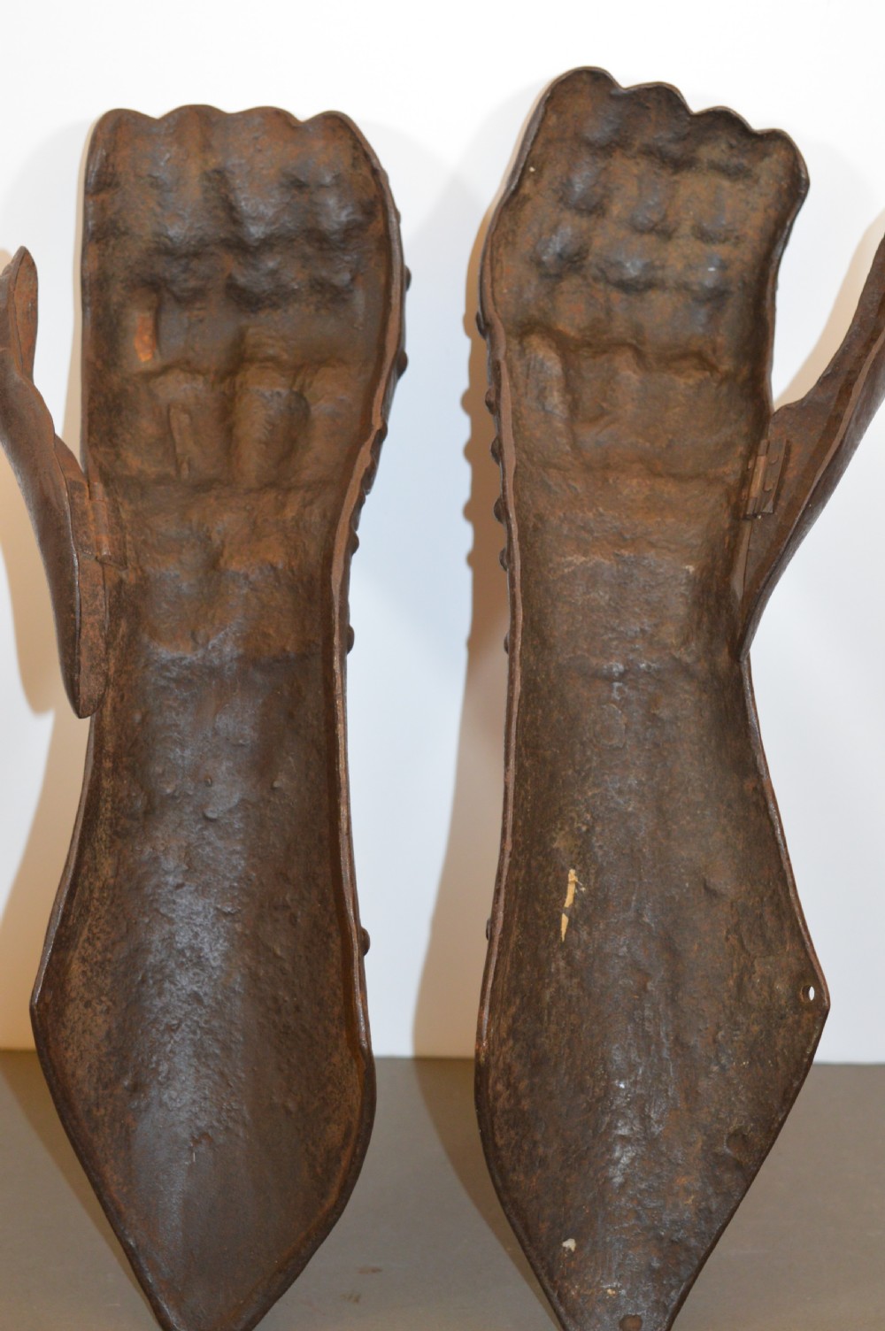 A pair of 19th-century articulated iron armour gauntlets with layered finger plates, flared cuffs, and visible rivets with an oxidised patina. View XII