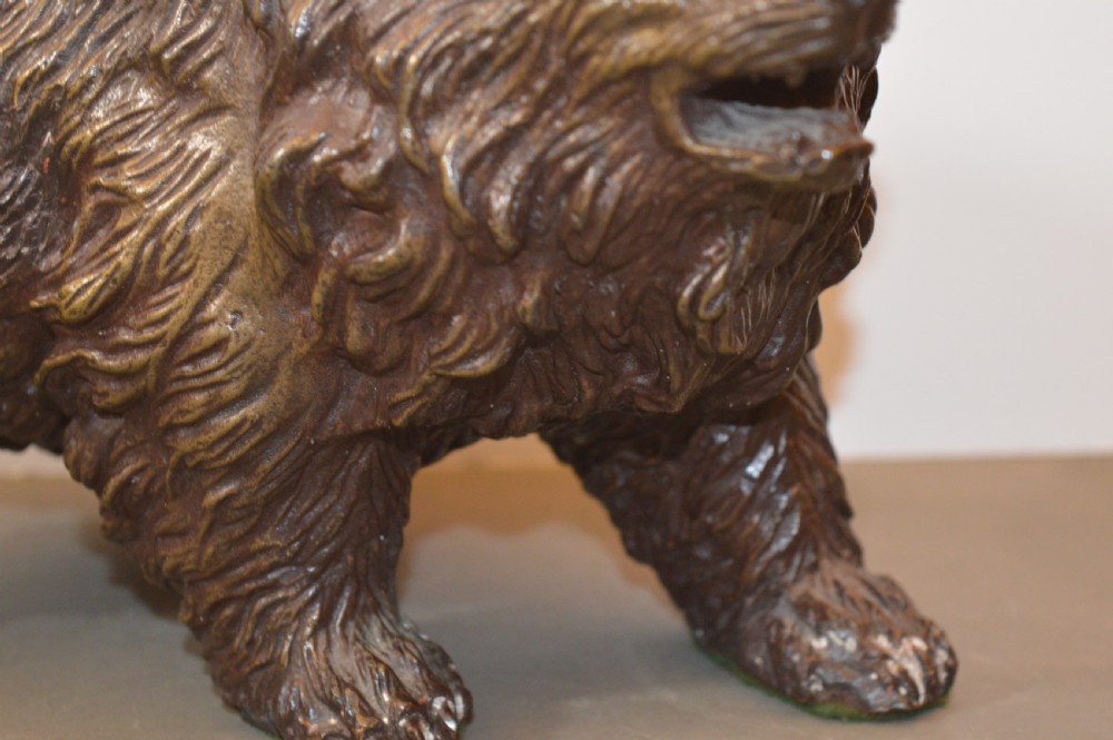 A heavy cast bronze sculpture depicting a bear with textured fur and an open mouth in a walking pose. View V