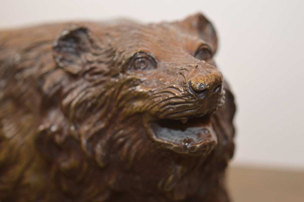 A heavy cast bronze sculpture depicting a bear with textured fur and an open mouth in a walking pose. View X