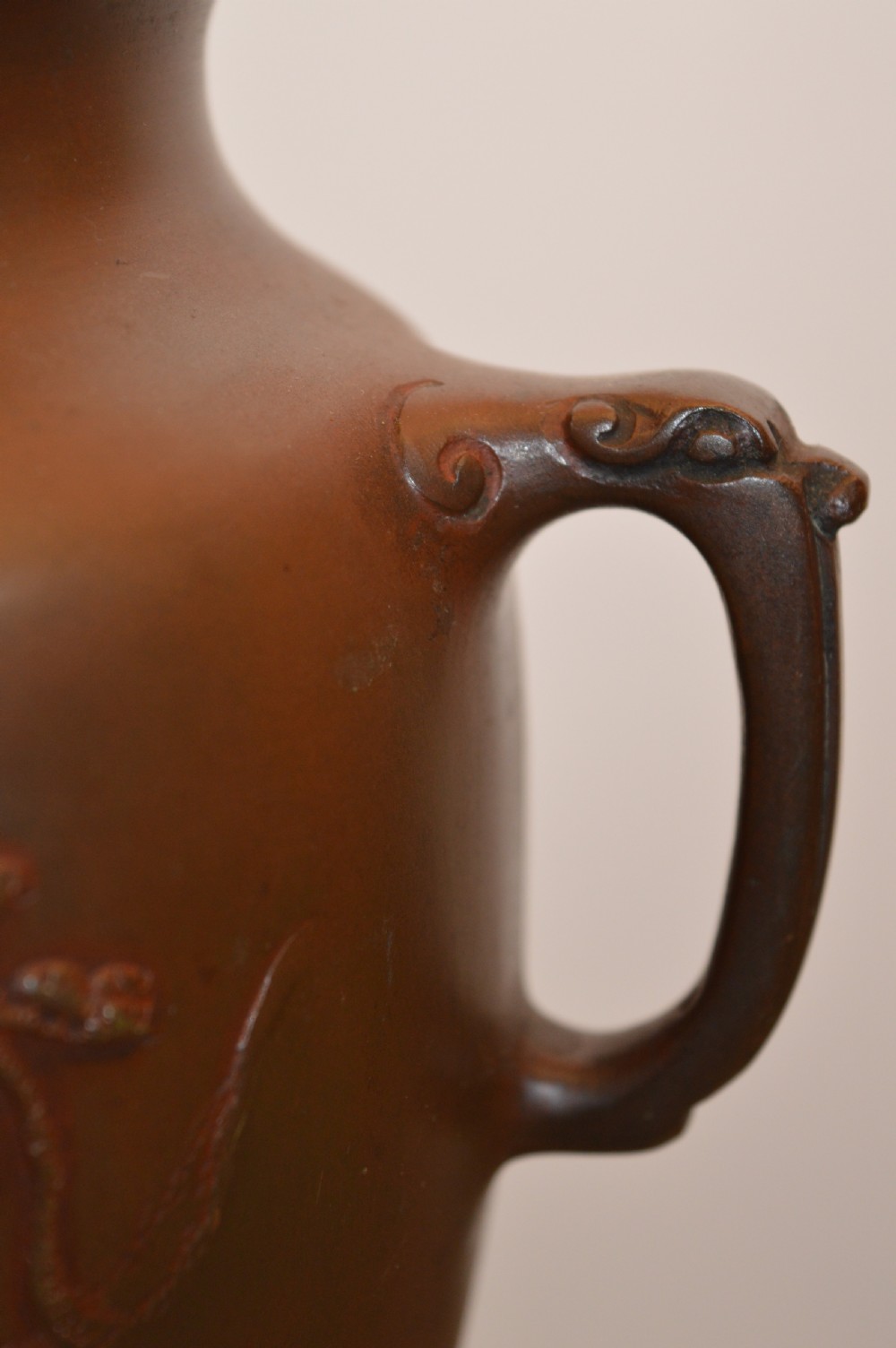 A Japanese Meiji period bronze urn featuring low relief carvings of pine trees and mountains with twin handles, resting on a matching carved bronze tripod stand. View XI