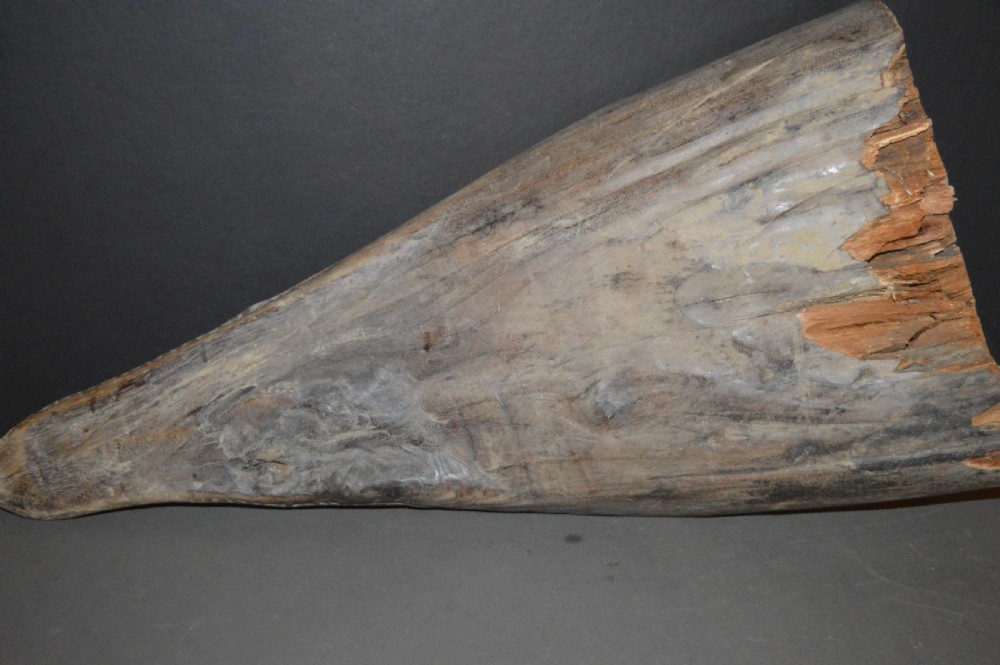 A carved wooden canoe prow shaped like a stylised crocodile head with weathered grey timber and incised geometric details around the eyes. View XVII
