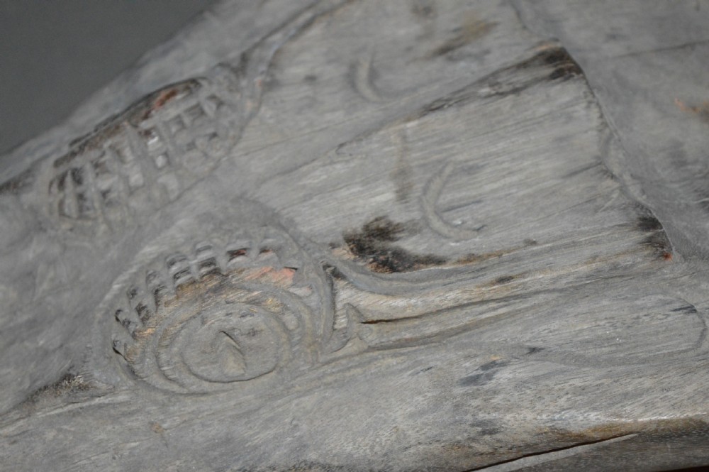 A carved wooden canoe prow shaped like a stylised crocodile head with weathered grey timber and incised geometric details around the eyes. View XVIII
