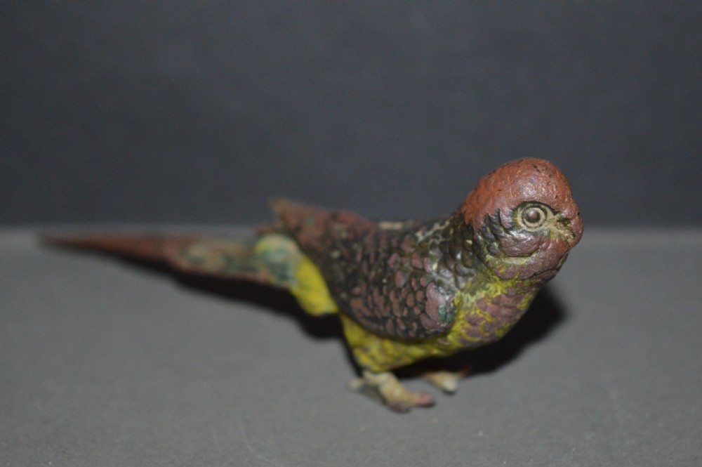 A cold-painted bronze figurine depicting a parrot with textured feather details in shades of brown, green, and yellow. View II