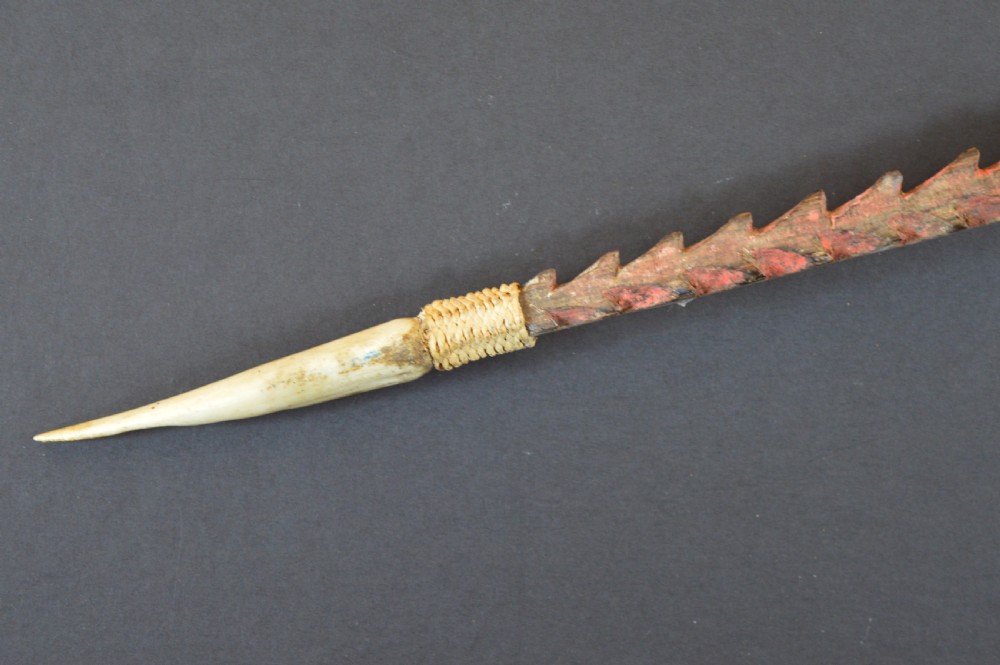 An antique Papua New Guinea fighting club featuring a angled wooden shaft, intricate woven rattan lashing, and a projecting serrated spike. View IV