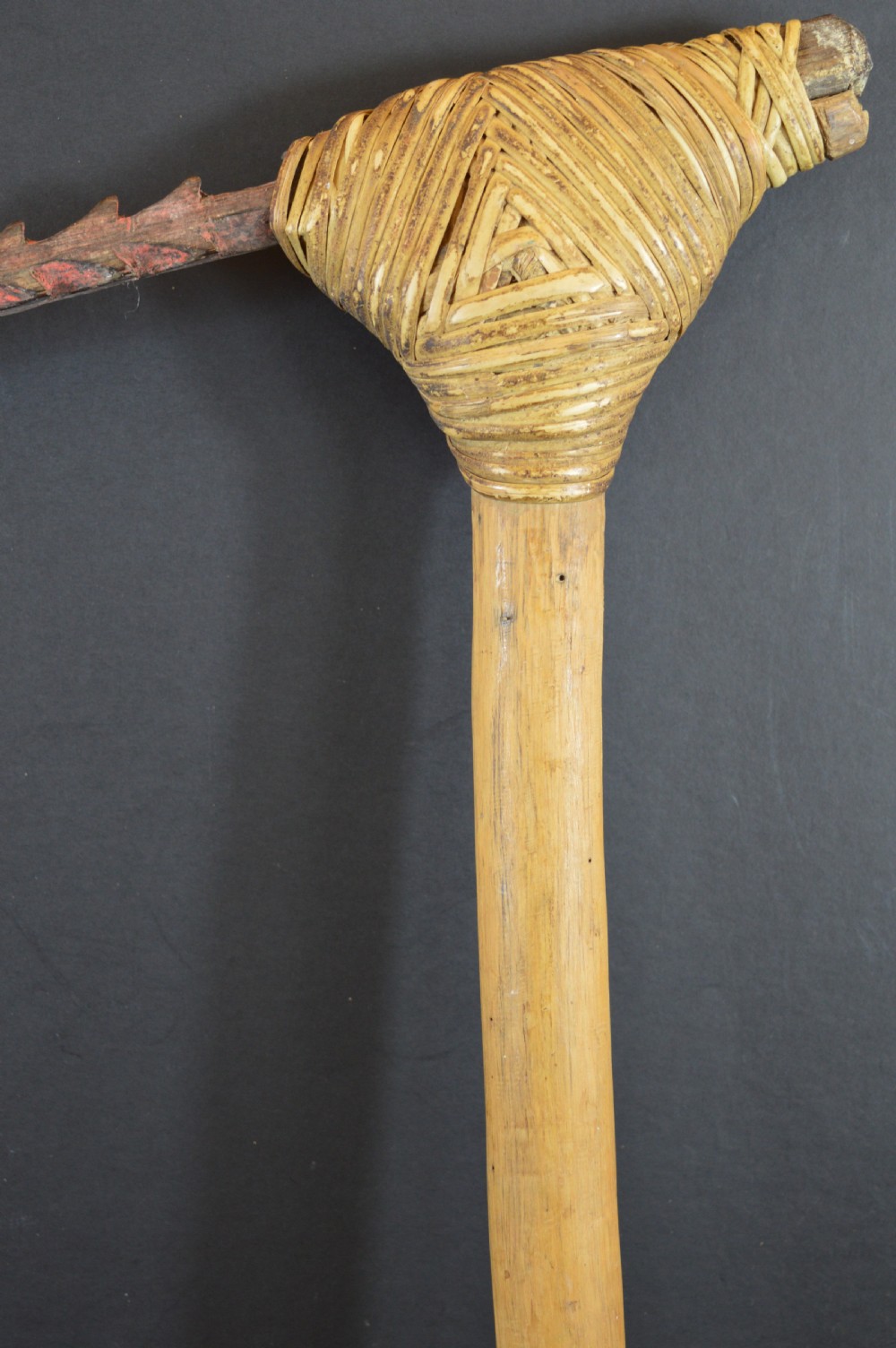 An antique Papua New Guinea fighting club featuring a angled wooden shaft, intricate woven rattan lashing, and a projecting serrated spike. View VI