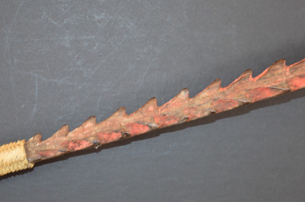 An antique Papua New Guinea fighting club featuring a angled wooden shaft, intricate woven rattan lashing, and a projecting serrated spike. View IX