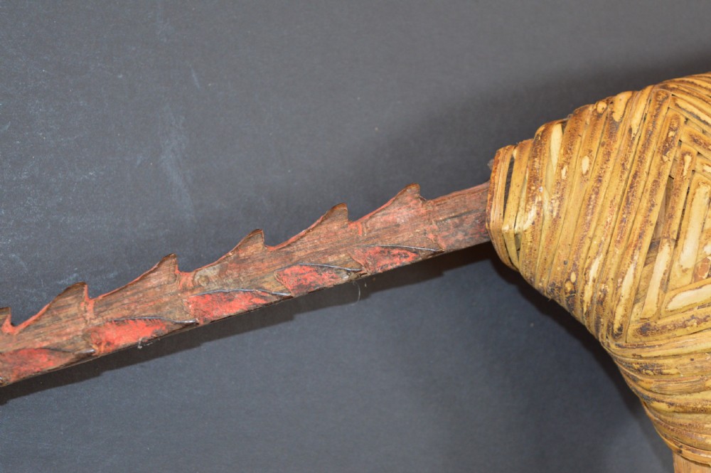 An antique Papua New Guinea fighting club featuring a angled wooden shaft, intricate woven rattan lashing, and a projecting serrated spike. View X