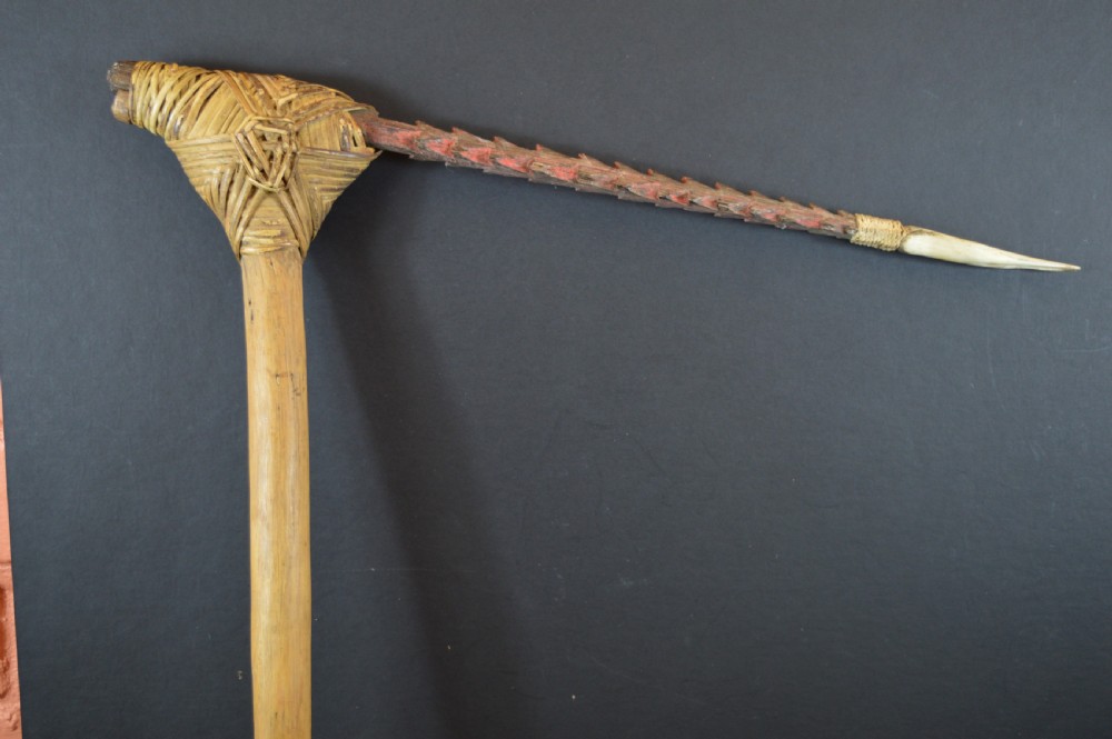 An antique Papua New Guinea fighting club featuring a angled wooden shaft, intricate woven rattan lashing, and a projecting serrated spike. View XIII