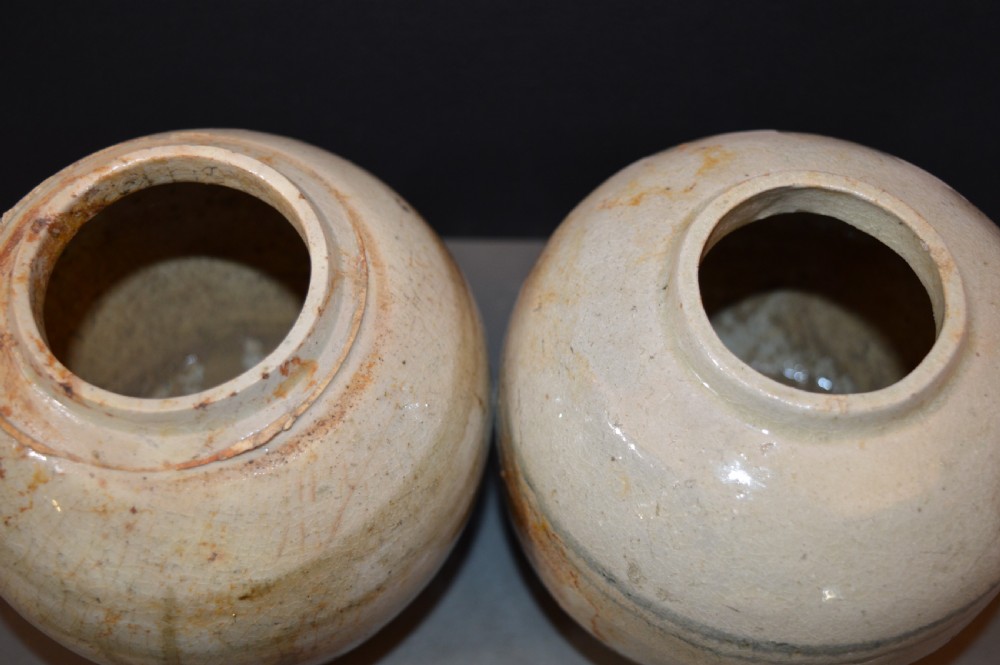 A pair of antique Chinese Ming dynasty ceramic pots featuring short rolled rims, globose bodies, and heavily crackled, patinated cream glazes. View IV