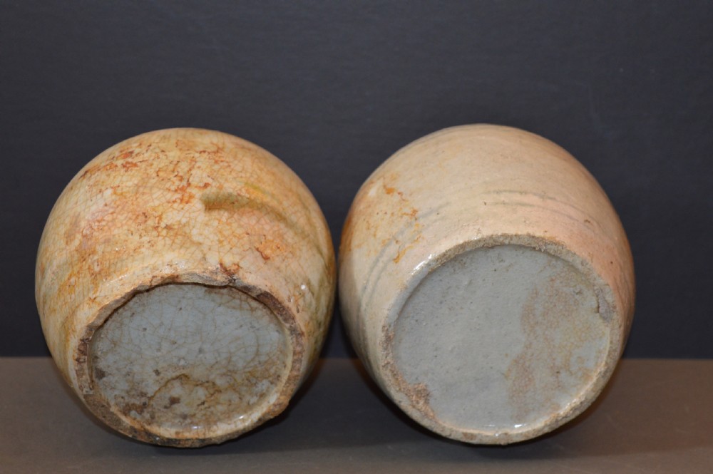 A pair of antique Chinese Ming dynasty ceramic pots featuring short rolled rims, globose bodies, and heavily crackled, patinated cream glazes. View V