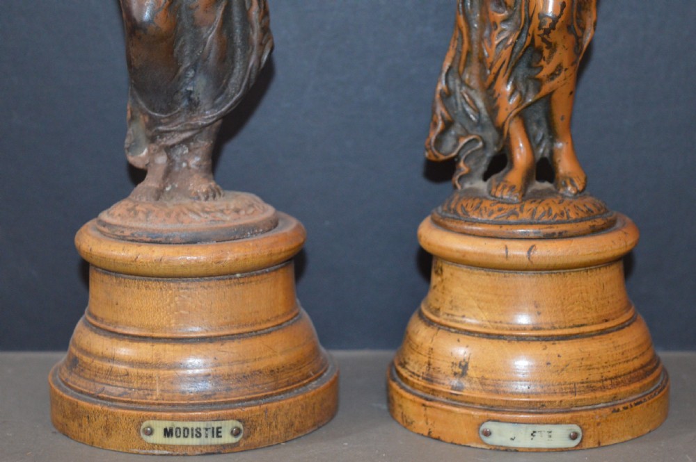 A pair of late nineteenth-century French bronzed metal allegorical female statues titled Modestie and Gaiete, mounted on circular turned wooden bases with brass nameplates. View III
