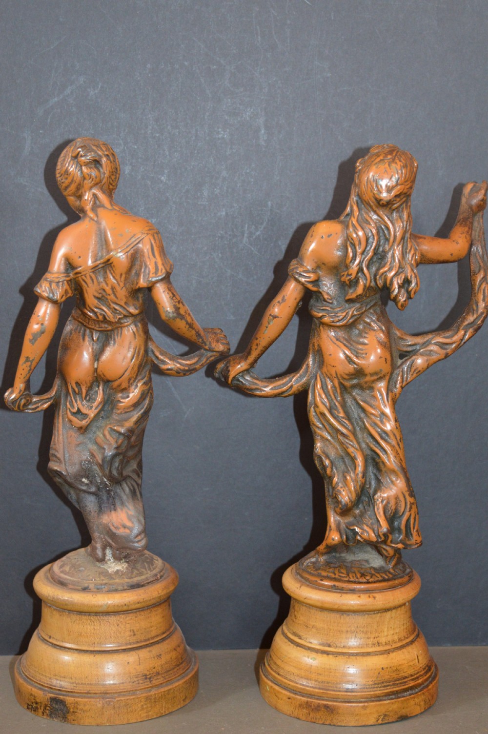 A pair of late nineteenth-century French bronzed metal allegorical female statues titled Modestie and Gaiete, mounted on circular turned wooden bases with brass nameplates. View VI